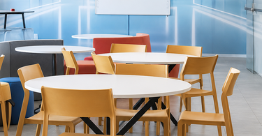 School library learning area featuring a futuristic blue 3D perspective wall mural, Honeywell branding, round tables, yellow chairs, and a mounted whiteboard.