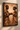Afro-modern framed canvas artwork displayed on a textured warm plaster wall, featuring two African figures exchanging a ceremonial vessel, presented in a thin matte black wood frame with visible depth, soft natural side lighting, and subtle shadow for a premium gallery-style interior setting.
