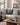 Neutral living room sofa styled with two grey and white geometric triangle NIZARRA Xhosa-inspired cushions and a textured grey cushion in an Afro-modern interior setting.