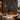 Contemporary hotel reception featuring NIZARRA Crossline 01 Charcoal geometric wallpaper mural, with intersecting bronze, stone and burgundy lines, dark reception desk and warm metallic accents.