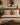 Two cream and rust-brown Setswana-inspired patterned cushions styled on a neutral bed in a warm Afro-modern bedroom with wood tones and African-inspired wall art.