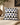 NIZARRA Xhosa-inspired geometric cushion in black, white, grey and cobalt blue styled on a textured cream armchair with warm natural accents.
