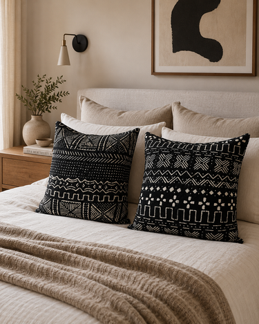 Decorative pillows with black and white patterns on a bed in a bedroom setting.