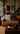 Portrait view of an industrial-style living room with a caramel leather sofa, black and cream geometric cushions, burgundy throw, dark wood coffee table, black ceramic décor, woven rug and concrete staircase.