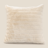 Cream faux fur cushion with soft horizontal channel detailing, shown on a warm neutral background for a clean product image.
