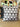 A square cushion with a geometric pattern inspired by Xhosa traditional designs, predominantly in grey and white colors.