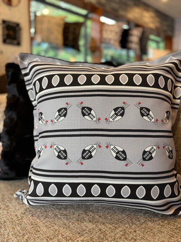 Decorative Swazi pillow with black and white pattern on a blurred indoor background