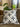 White cushion with black and grey Basotho-inspired motifs styled on a neutral sofa beside leafy greenery.