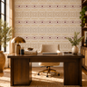 Contemporary home office with NIZARRA Pulse geometric wallpaper behind a dark wood desk, featuring burgundy circular motifs, earthy brown and grey patterns, an upholstered chair and bronze desk lamp.