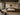 Contemporary African bedroom interior with a low timber bed, neutral bedding, geometric wall art, textured rug, black metal lighting, natural wood furniture and warm earthy styling.