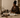 Black interior designer seated in a calm Afro-modern studio, reviewing design notes on a tablet beside material samples, a sketchbook, ceramic vessel, and warm neutral interior details.