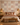 Terra Rhythm mud cloth-inspired wallpaper by NIZARRA behind an upholstered bed, styled with terracotta cushions, natural woven textures and warm wooden furniture.