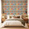 Modern bedroom with NIZARRA Zulu-inspired geometric wallpaper featuring colourful diamond motifs, earthy triangles and black-and-ivory detailing behind a neutral upholstered bed.