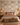 Terra Rhythm mud cloth-inspired wallpaper by NIZARRA behind an upholstered bed, styled with terracotta cushions, natural woven textures and warm wooden furniture.