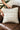 Person holding a decorative pillow with geometric pattern on a brown leather couch.